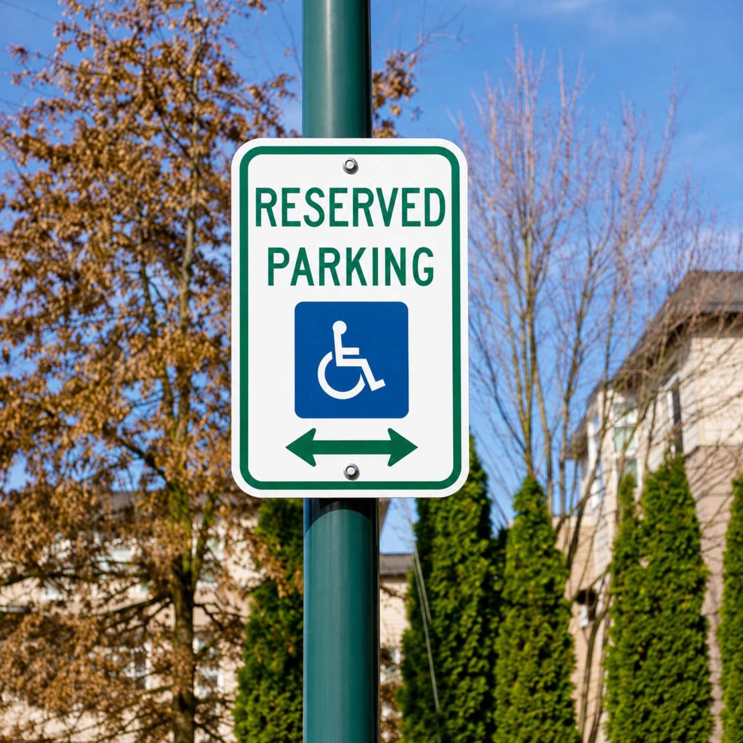 White 12"x18" reserved handicap parking sign with green border, blue symbol, and double arrows on a pole.
