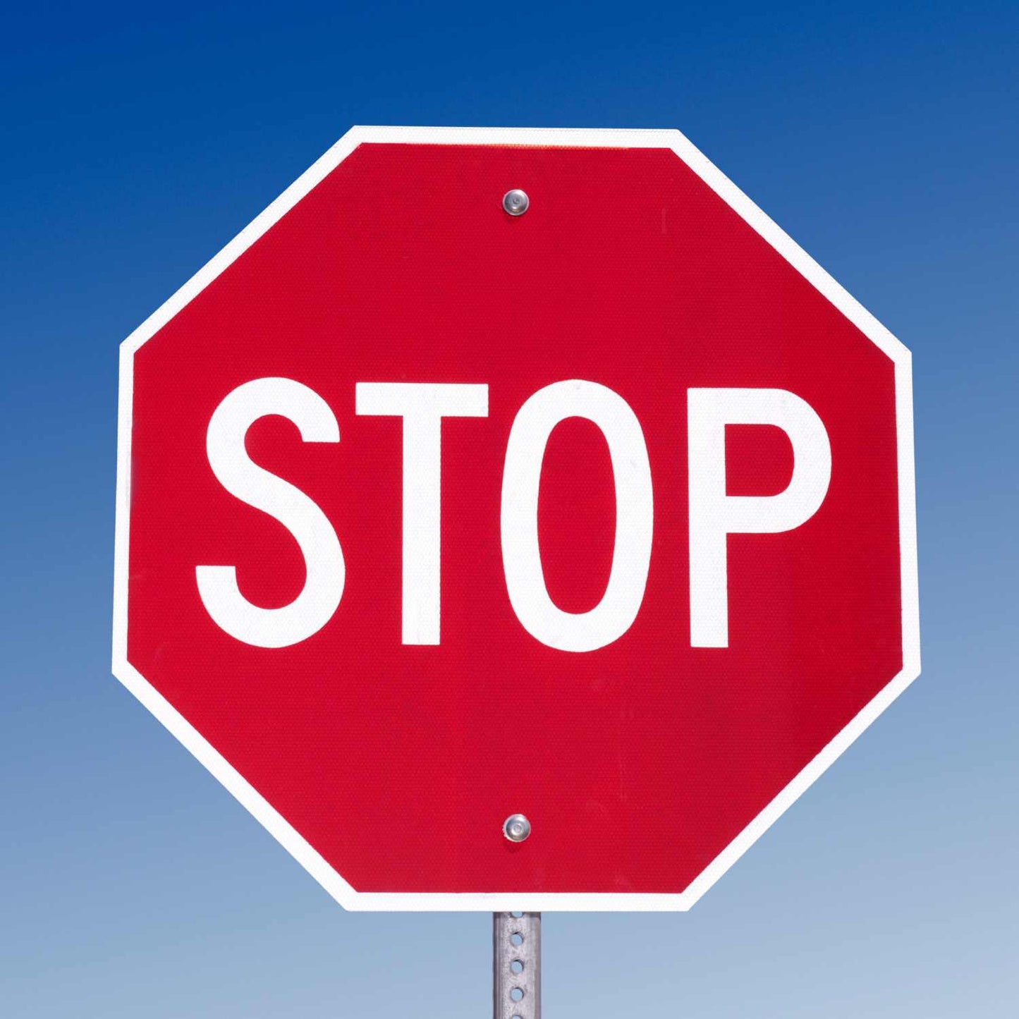 Red octagonal MUTCD STOP sign (R1-1) with white legend, made from reflective aluminum, mounted on a pole.
