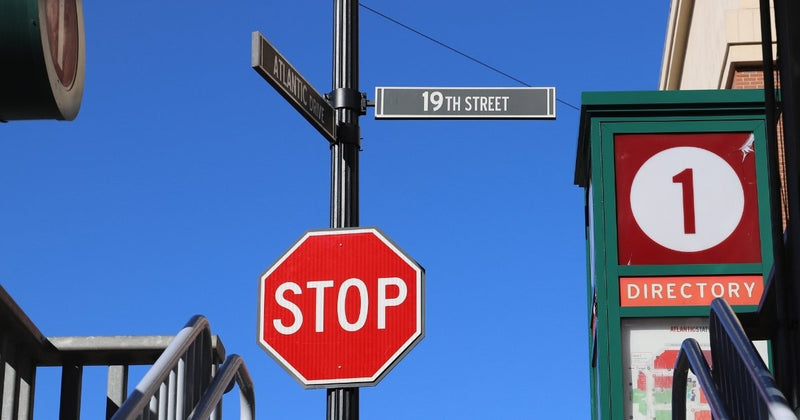 A stop sign mounted on a black pole under two street name signs on top