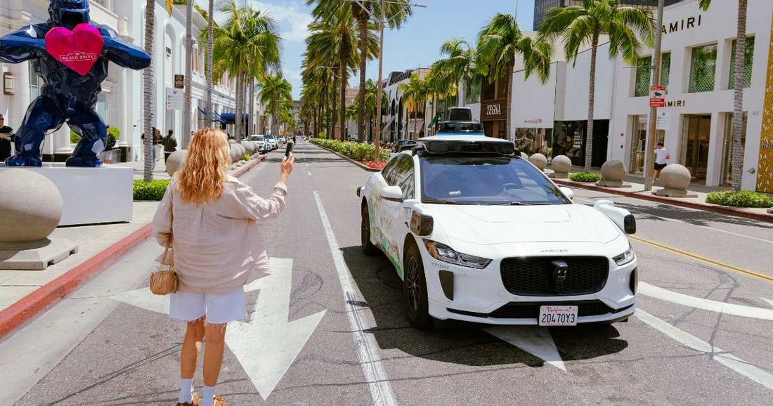 A woman taking a picture of a Waymo car in the middle of the street in California