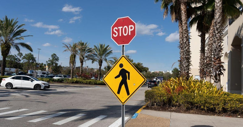 Standard red octagonal stop sign mounted above a yellow diamond-shaped pedestrian crossing sign on a metal post.