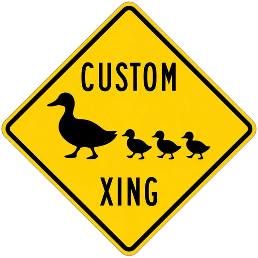 A yellow diamond-shaped warning sign with a black border, black text reading 'CUSTOM XING,' and a black silhouette of a duck with three ducklings, shown on a plain white background.