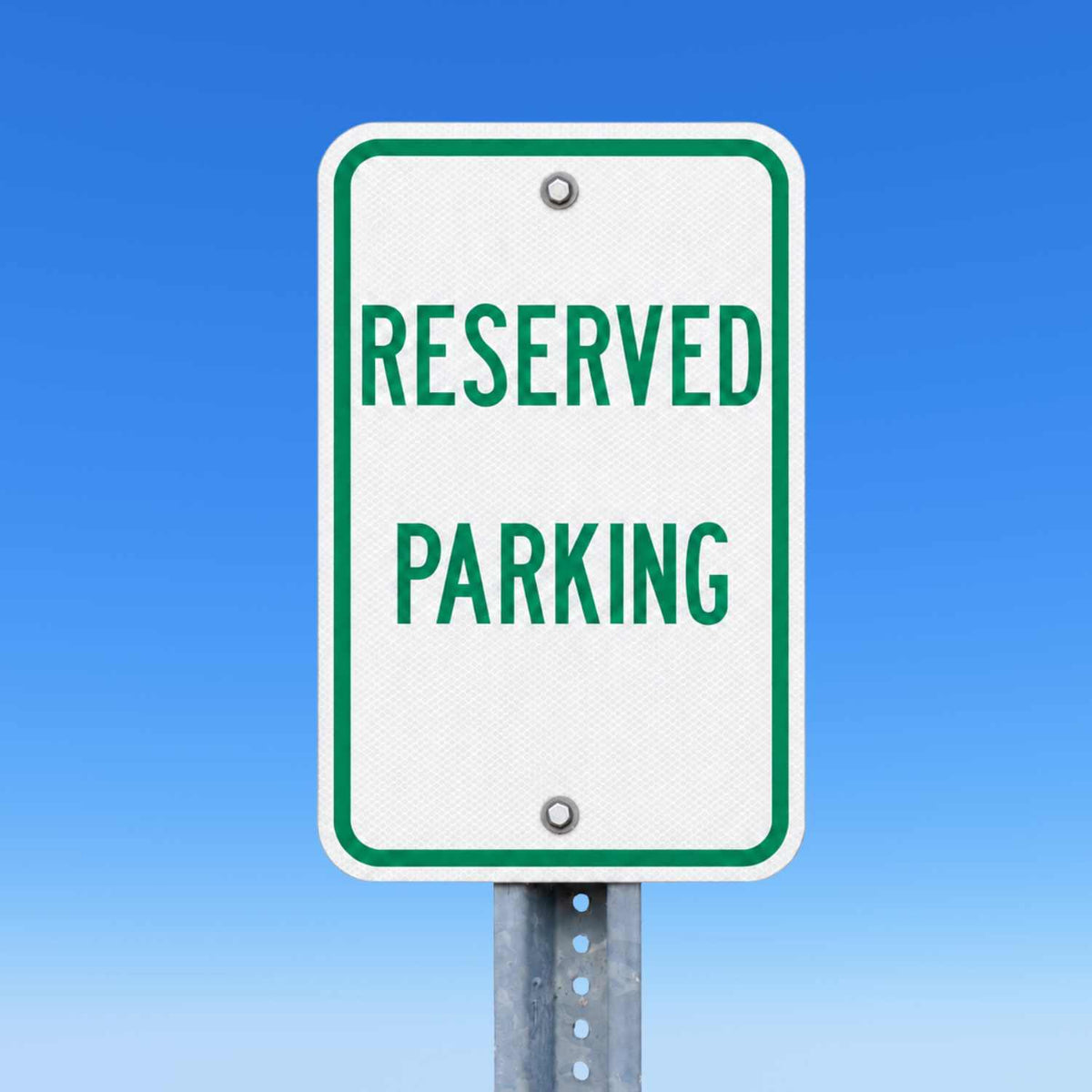 White 12"x18" reserved parking sign with green text and border, mounted on a metal post.