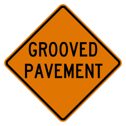 Orange diamond-shaped CW8-15 construction sign with black GROOVED PAVEMENT legend.