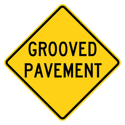 Yellow diamond-shaped W8-15 warning sign with black GROOVED PAVEMENT legend.