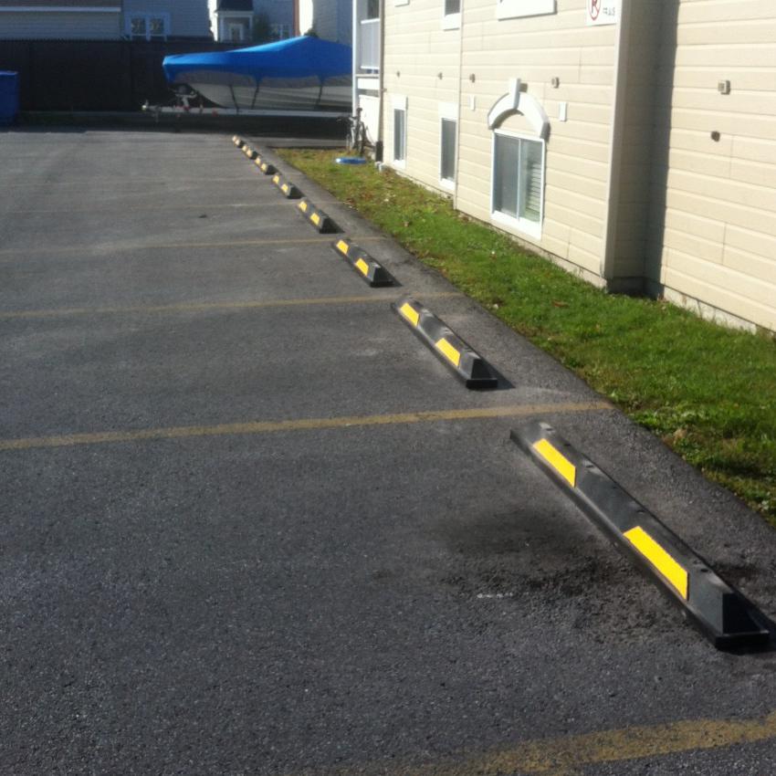 Rubber parking blocks with yellow strips at the head of parking spaces