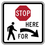 White square sign with black border, red octagonal "STOP" and "HERE FOR" with a right arrow, and pedestrian symbol.